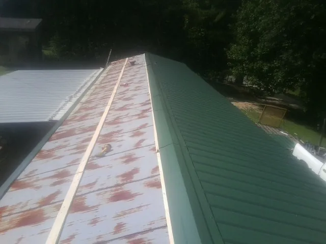 Old rusted panels beside newly installed green metal roofing — Wind Damage Roof Repair by Roofing Brothers in Warrenton