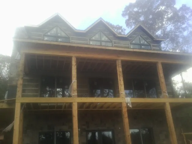 Dormers and porch framing on a large log home under construction — Roof Coating work by our crew in Warrenton