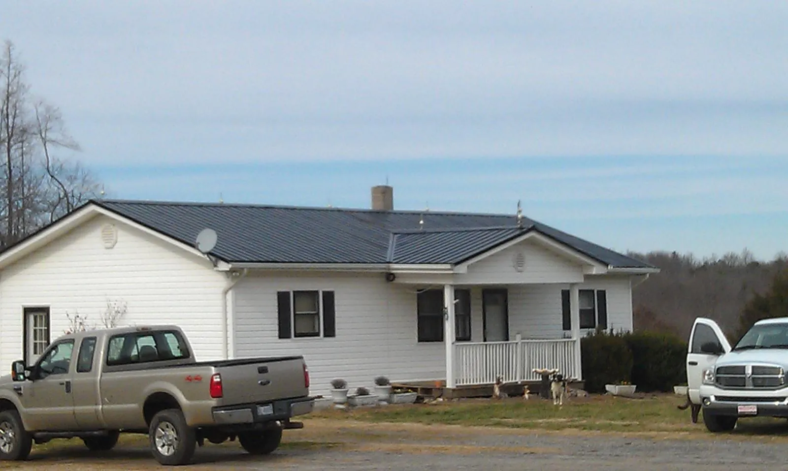 Finished dark metal roof on a white ranch home with work trucks parked in Warrenton